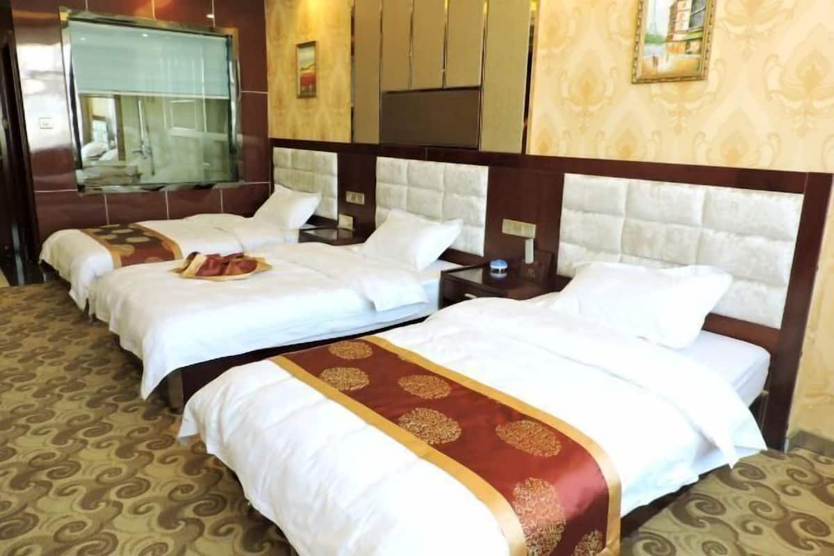 Habitación de hotel con dos camas, cada una con ropa blanca y un corredor decorativo rojo.