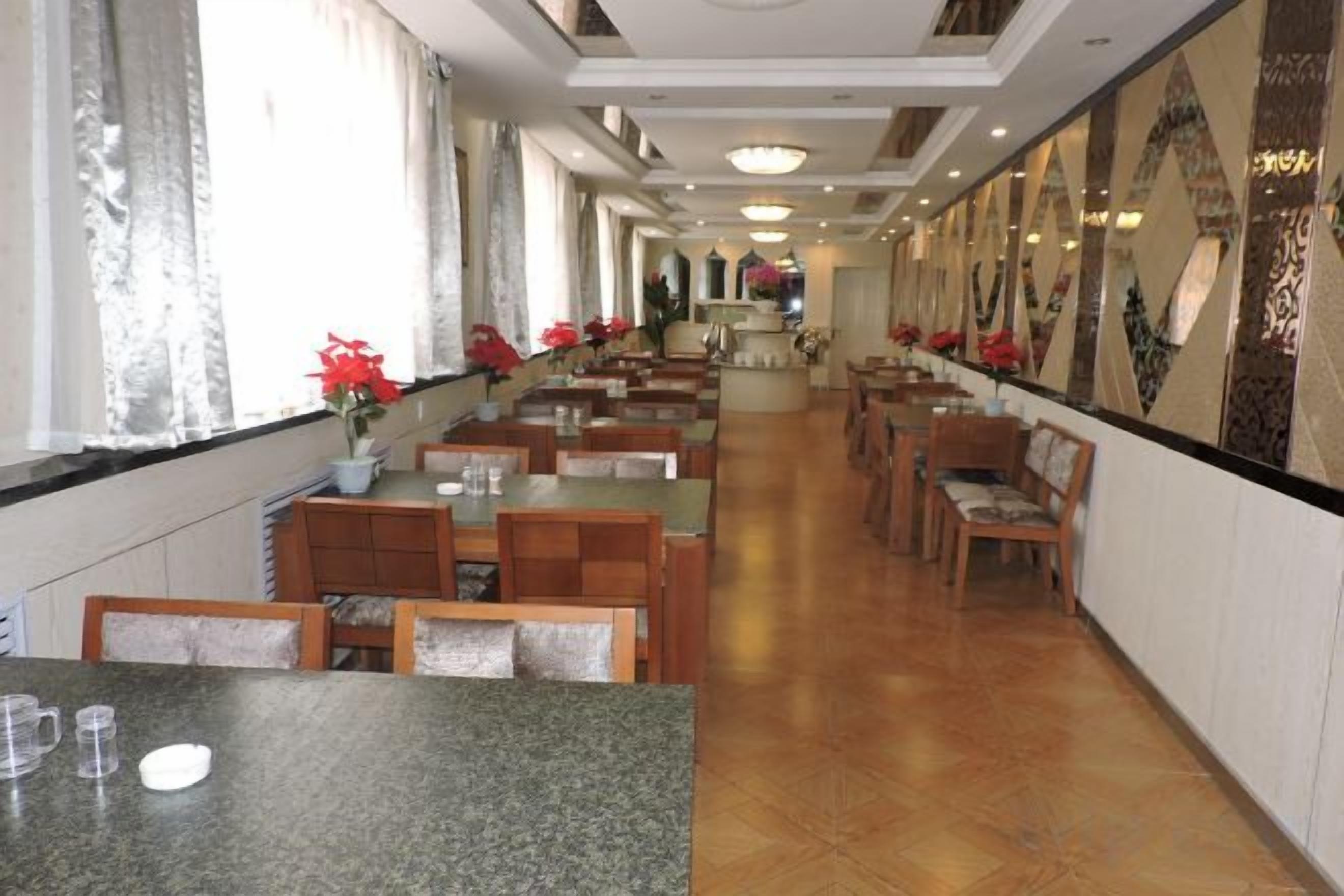 A long dining area with tables and chairs, a counter, and a view of the corridor.
