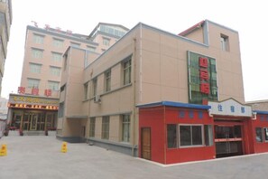 A multi-story building with a red and beige facade, featuring signage for a fitness center and a health club. - Feitian Hotel (Jingyuan)