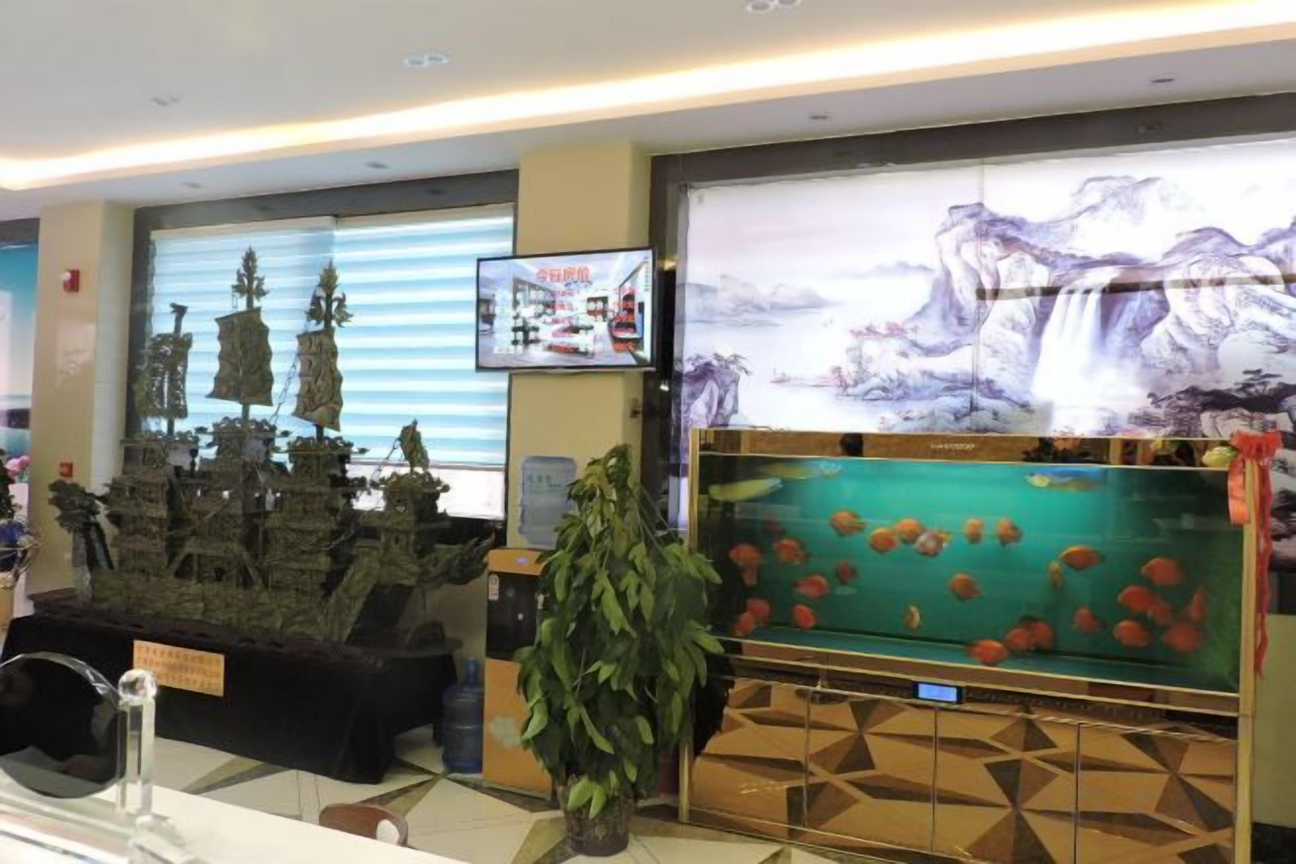 A reception area with a large screen displaying a waterfall, a model of a traditional building, and a potted plant.