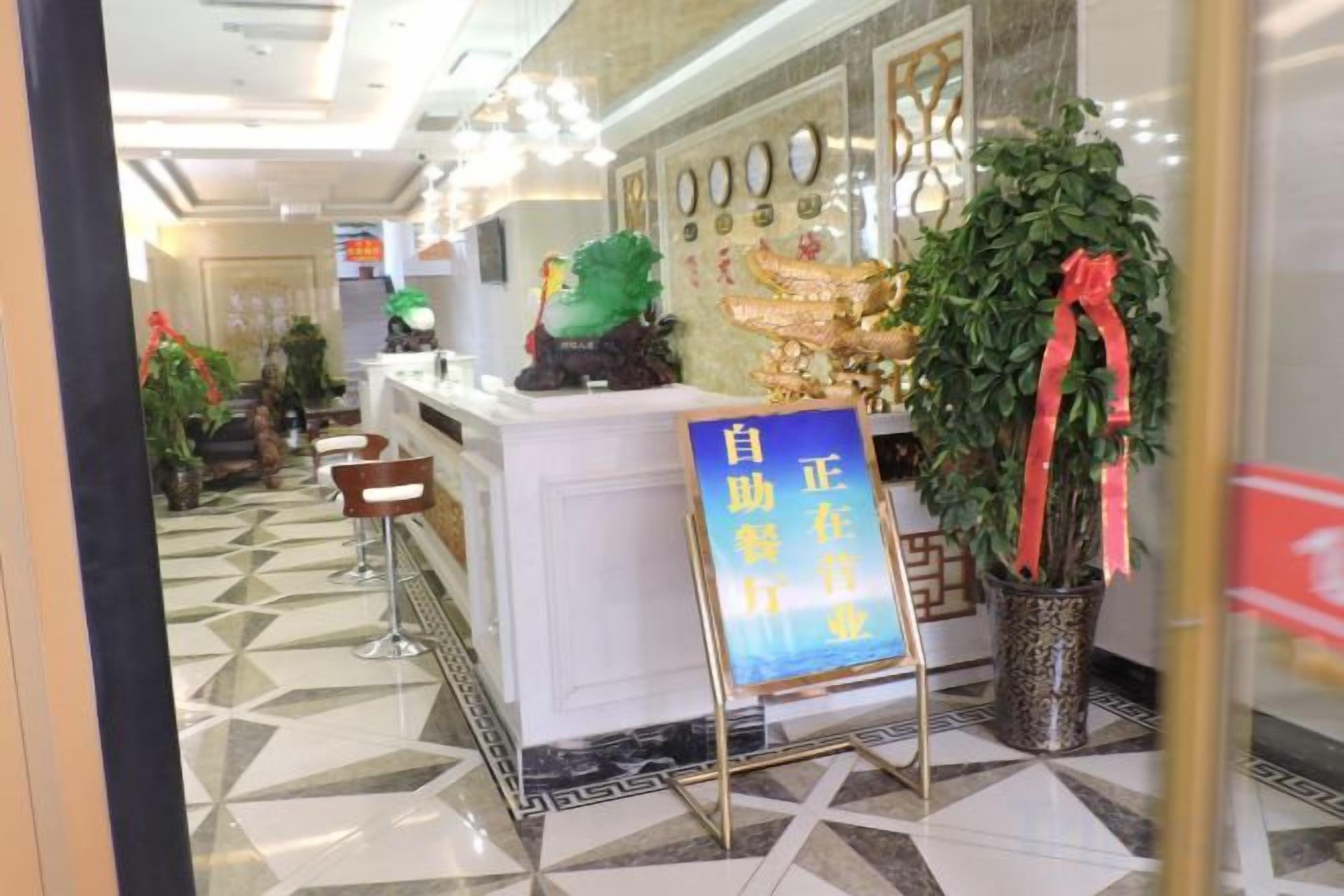 A reception area with a counter, a sign, and potted plants.