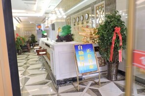 A reception area with a counter, a sign, and potted plants. - Feitian Hotel (Jingyuan)