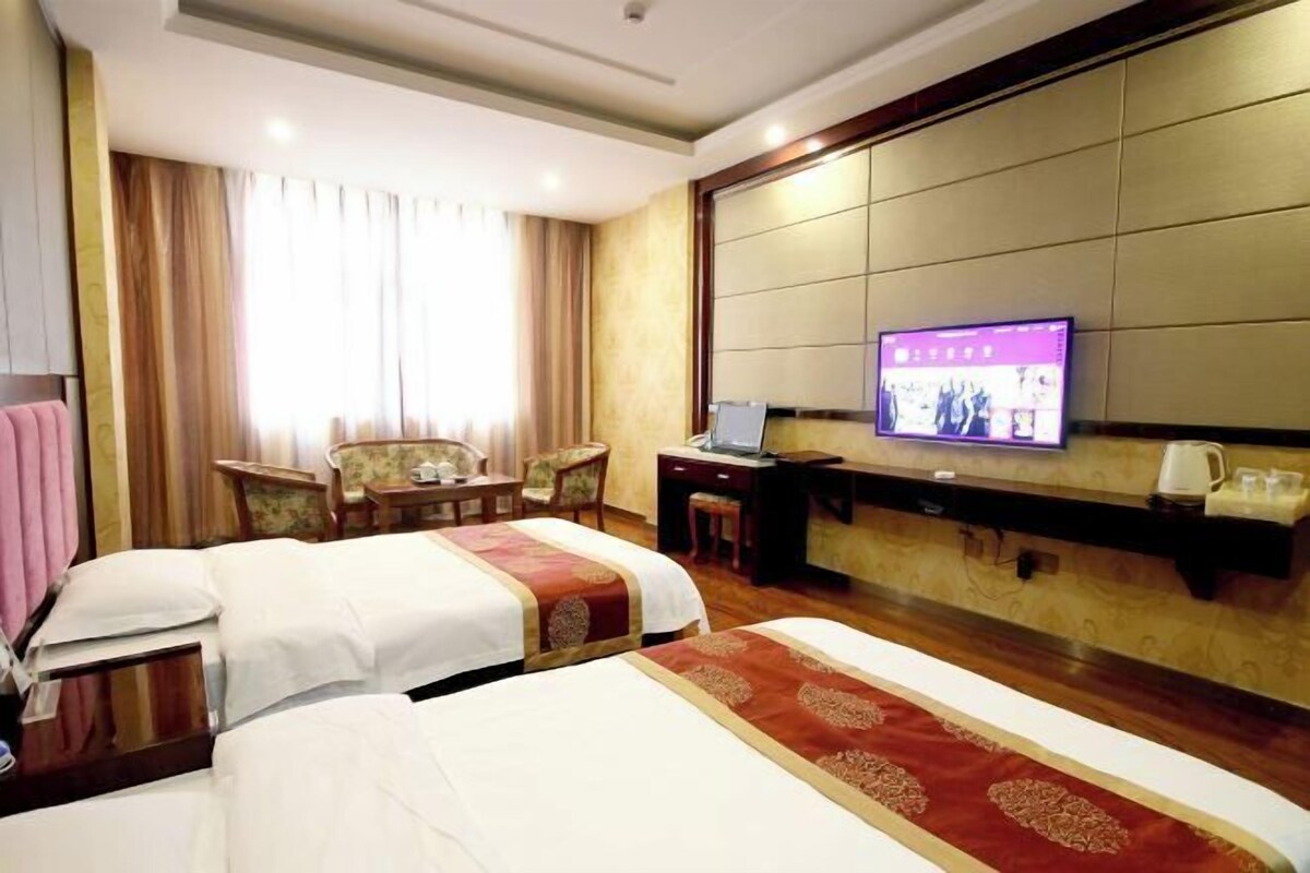 Ein Hotelzimmer mit zwei Betten, einem Schreibtisch, einem Fernseher und einer Sitzecke mit Stühlen und einem Tisch.