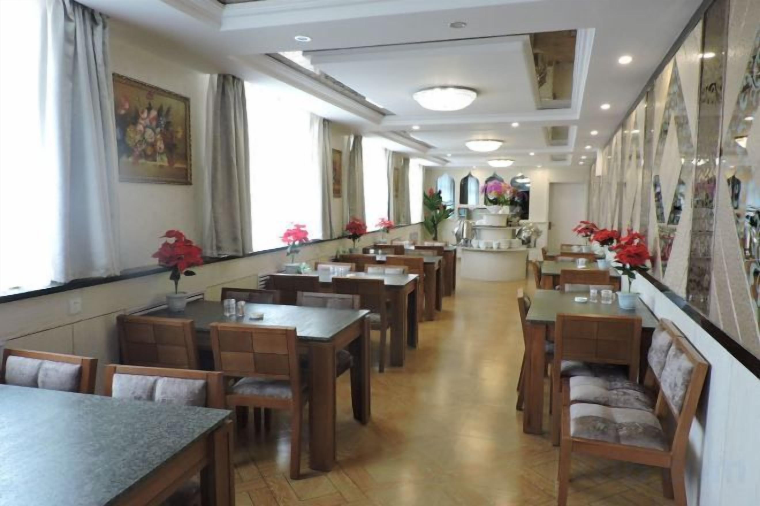 A restaurant with multiple tables and chairs, a long counter, and a view of the kitchen area.