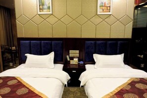 A hotel room with two beds, a nightstand with a lamp, and a wall-mounted TV. - Feitian Hotel (Jingyuan)