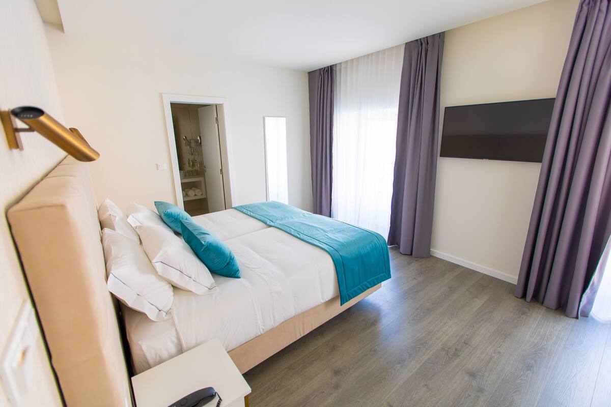 A modern bedroom with a bed, bedside table, and a TV mounted on the wall.