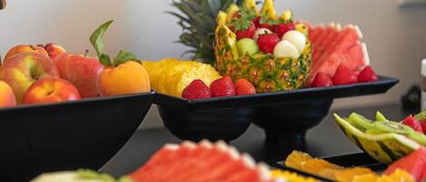 Una bandeja de frutas con manzanas, naranjas, sandía y piña.