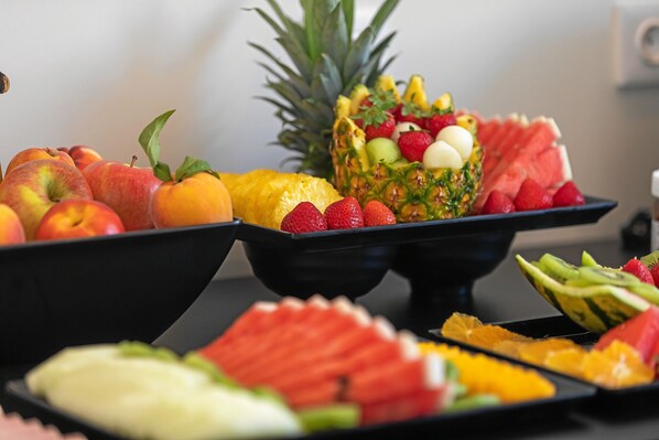 Una bandeja de frutas con manzanas, naranjas, sandía y piña.
