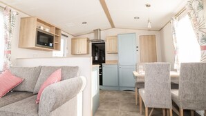 A compact RV interior with a kitchenette, a sofa, and a dining area. - 109 Bude (Truro)