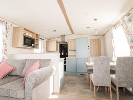 Interior compacto de autocaravana con kitchenette, sofá y zona de comedor.