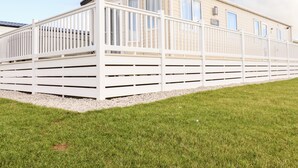 A single-story mobile home with a white exterior, a covered porch, and a gravel driveway. - 109 Bude (Truro)