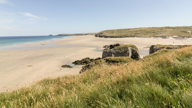 A coastal landscape with a sandy beach, grassy dunes, and rocky outcrops. - 109 Bude (Truro)