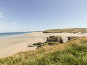A coastal landscape with a sandy beach, grassy dunes, and rocky outcrops. - 109 Bude (Truro)