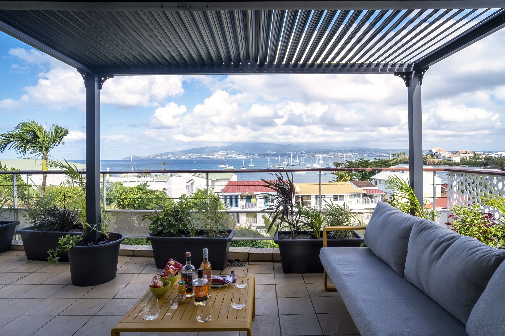 Un espacio al aire libre cubierto con un sofá, una mesa y plantas en macetas.