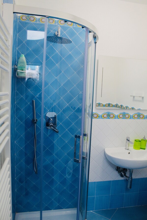 Ein Badezimmer mit einer Duschkabine, einem weißen Waschbecken und blauen Fliesenwänden.