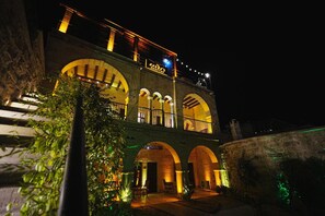 A building with multiple arches and balconies, illuminated by warm lighting. - Kayra Cave Suites (Nevsehir)