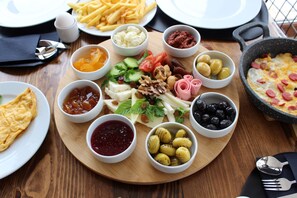A wooden table with a variety of food items and a pan with eggs. - Kayra Cave Suites (Nevsehir)