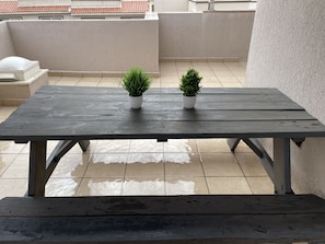 Enjoy a meal or a moment of relaxation at this outdoor table, surrounded by lush greenery and a serene atmosphere.