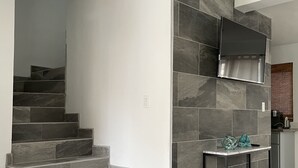 Une cuisine moderne avec des murs recouverts de carreaux gris, une cuisinière encastrée et une petite table agrémentée d’objets décoratifs.
