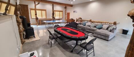 A spacious living area with a ping pong table, a sofa, and a wooden beam ceiling.