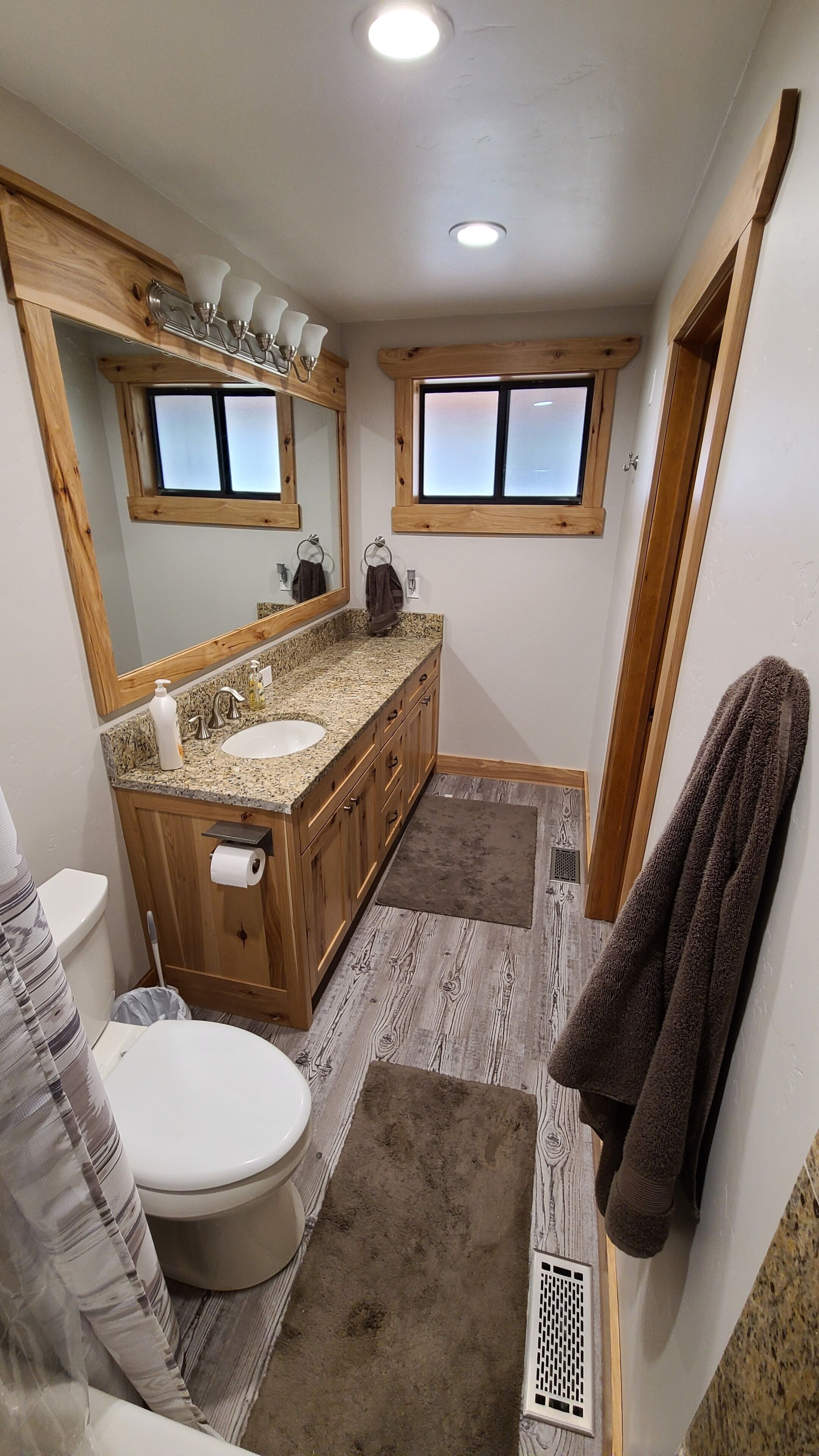 A bathroom with a wooden vanity, a sink, a toilet, and a shower area.