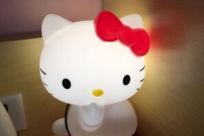 Hello Kitty -aiheinen yövalo, jossa on punainen rusetti ja joka on asetettu puupinnalle.
