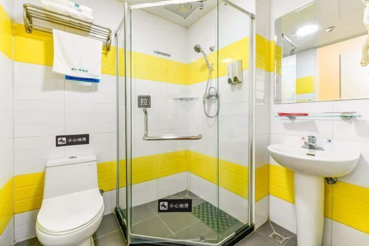 A bathroom with a glass shower enclosure, a white sink, and a toilet.