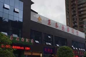 A hotel with a prominent sign and multiple storefronts below. - Monai Garden Hotel (Youyang County)