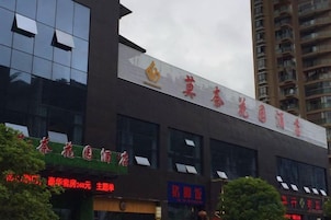 Un hotel con un letrero llamativo y varios comercios en la planta baja.