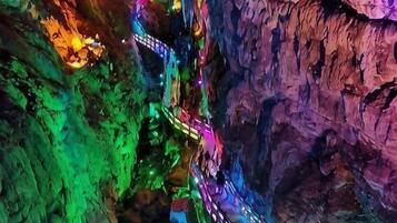 Una cueva con un estrecho pasaje iluminado por luces de colores.