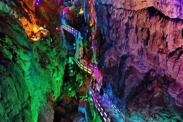 A cave with a narrow passageway illuminated by colorful lights.