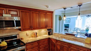 A kitchen with wooden cabinets, stainless steel appliances, and a wooden floor. - Unique Waterfront Condo at the Boatyard! (Kennebunk)