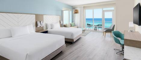 Habitación de hotel con dos camas, un escritorio, una silla y un balcón con vista al mar.