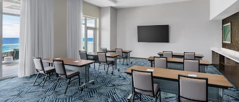 Un salón de conferencias con una gran mesa, sillas y una televisión en la pared.