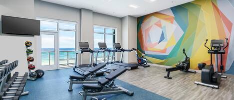 Un gimnasio con máquinas de cardio, bancos de pesas y mancuernas.