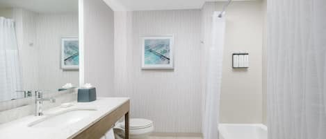 Un baño moderno con lavamanos de mármol, inodoro, bañera y dos cuadros enmarcados en la pared.