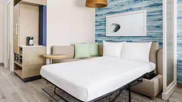 Een hotelkamer met een bed, een bank, een koffieapparaat en een wand met een ingelijst kunstwerk.