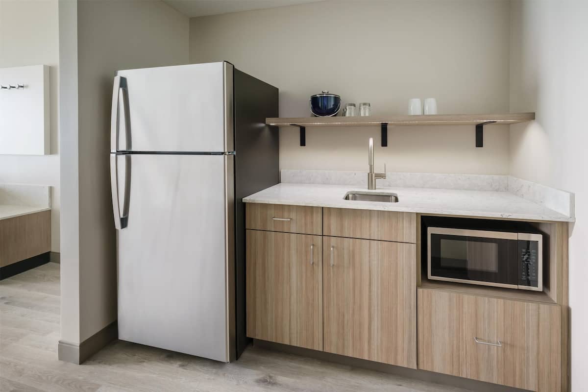 A modern kitchen with a built-in refrigerator, a microwave, and wooden cabinets.