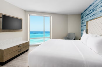 A conference room with round tables, chairs, and a large TV screen. at Hyatt Place Panama City Beach