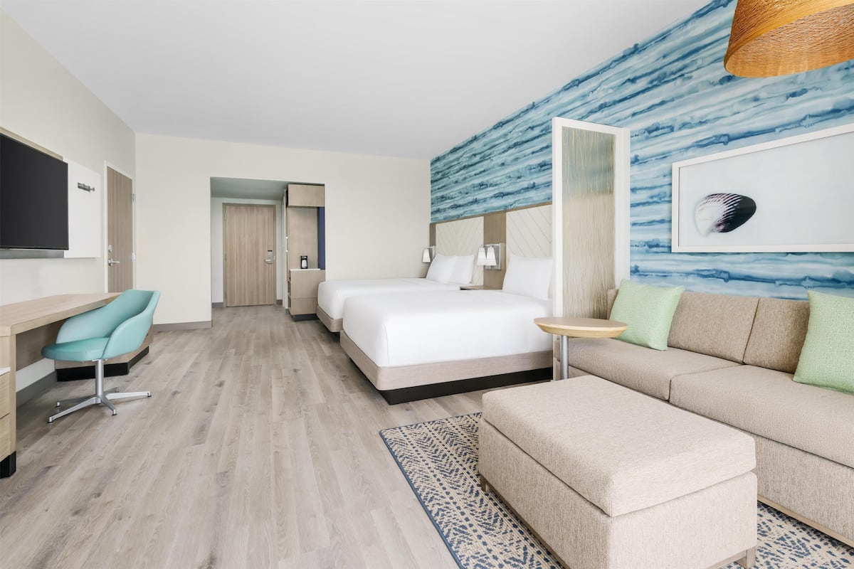 A hotel room with a bed, a sofa, a desk, and a TV.