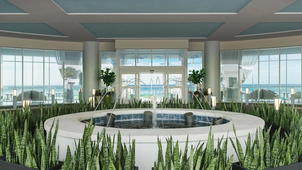 A spacious indoor area with a central water feature surrounded by planters, large windows offering views of the sea, and a modern architectural design. - Hyatt Place Panama City Beach (Panama City Beach)