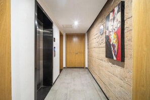 Een gang met een houten wand, een schilderij en een lift.