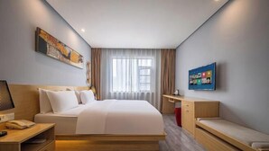 Une chambre d’hôtel moderne, dotée d’un grand lit, d’un bureau, d’une chaise, d’une télévision et d’une fenêtre avec des rideaux.