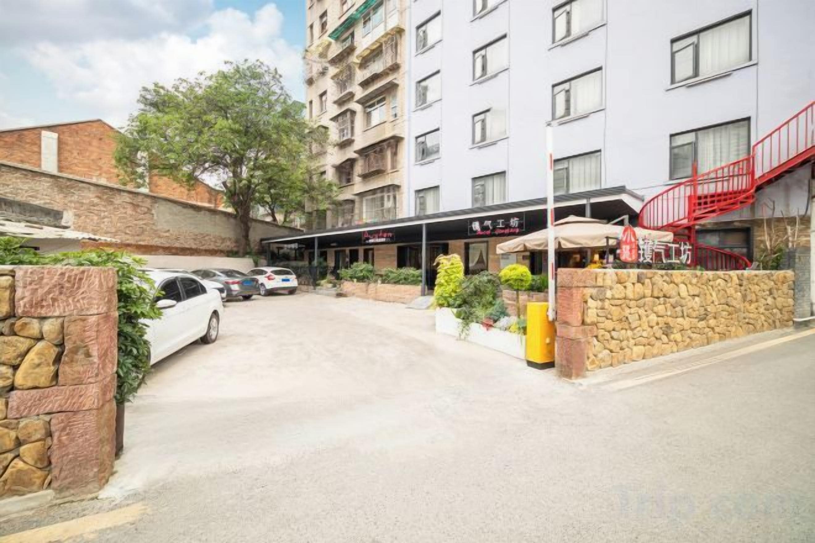 A hotel entrance with a covered walkway, a stone wall, and a red staircase.