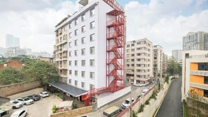 Un hôtel à plusieurs étages, doté d’une échelle de secours rouge bien visible, d’un parking et offrant une vue sur le quartier urbain environnant.
