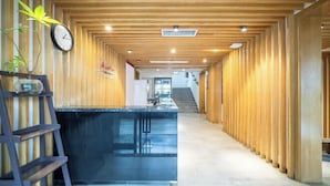 Un couloir aux murs lambrissés, avec une horloge, un bureau et un escalier au fond.