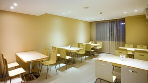 Une salle de conférence dotée de plusieurs tables et chaises, d’une grande fenêtre avec des rideaux et d’un éclairage encastré au plafond.