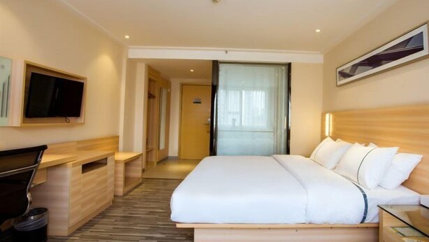Une chambre d’hôtel comprenant un lit, un bureau, une télévision et une porte donnant sur une autre pièce.