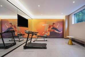 A modern gym with treadmills, a bench, and a wall-mounted TV. - City Comfort Inn (Guilin)