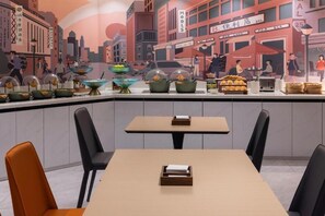 A restaurant with a cityscape mural, a variety of dishes displayed on the counter, and a seating area with tables and chairs. - City Comfort Inn (Guilin)